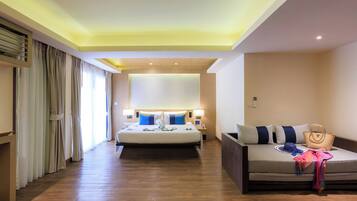 A hotel room with a bed, a sofa, a bedside table, a lamp, and a large window with curtains.