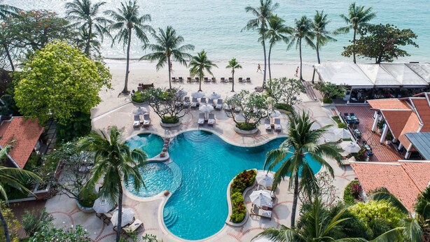 Un complexe hôtelier doté d’une piscine centrale, de palmiers et d’un accès à la plage.