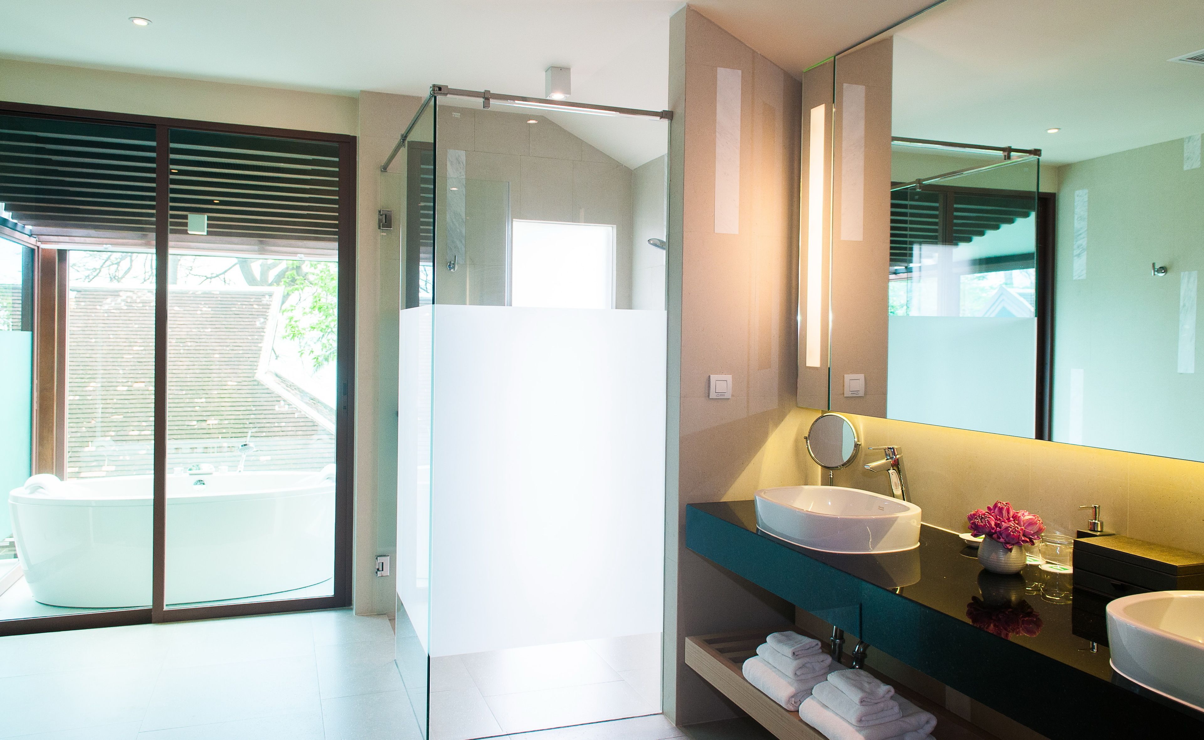 A modern bathroom with a glass shower enclosure, a white bathtub, and a vanity with a large mirror.