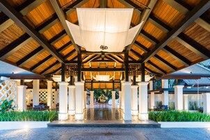 A covered outdoor area with a central light fixture, white pillars, and a tiled floor.