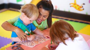 A child coloring with a woman and another child.