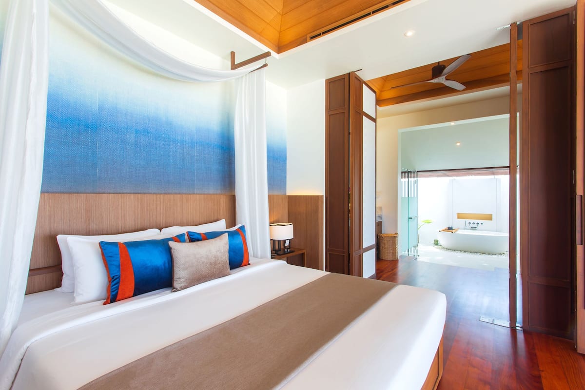 Amplia habitación con una cama grande, techo de madera y vistas a un baño con bañera.