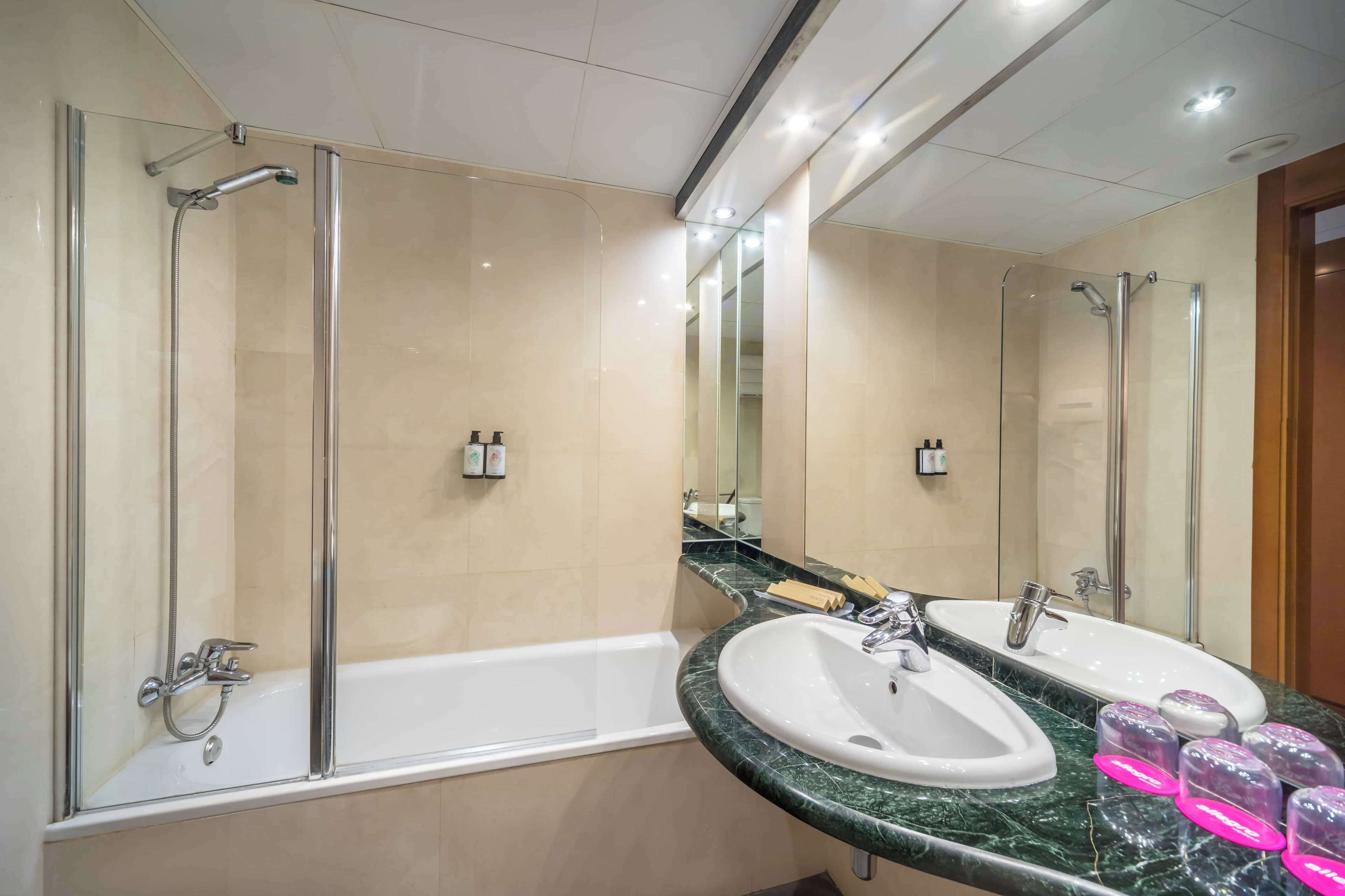 Un baño moderno con bañera, dos lavamanos y ducha con mampara de vidrio.