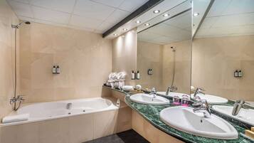 Un baño moderno con bañera, dos lavamanos y un espejo grande.