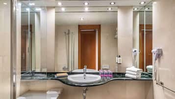 A modern bathroom with a large mirror, a sink, a shower, and a hairdryer.