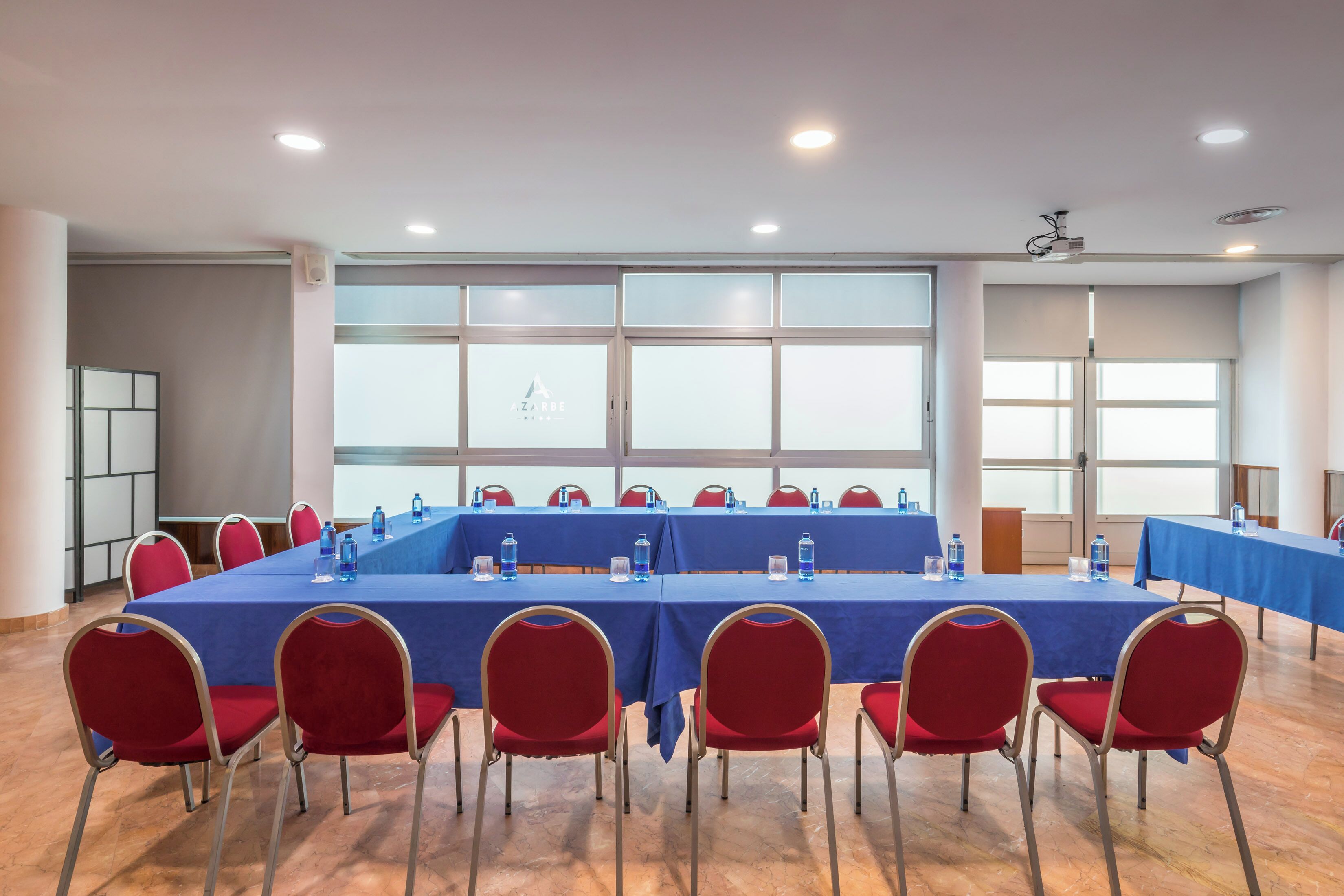 Ein Konferenzraum mit langem Tisch, roten Stühlen und großen Fenstern.