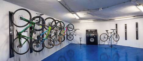 Habitación con piso y paredes azules, equipada con varias bicicletas sujetas a un soporte.