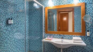 A bathroom with a white sink, a mirror, and blue mosaic tiles.