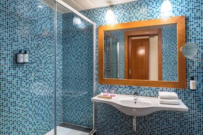 Une salle de bain avec un lavabo blanc, un miroir et des carreaux de mosaïque bleus.