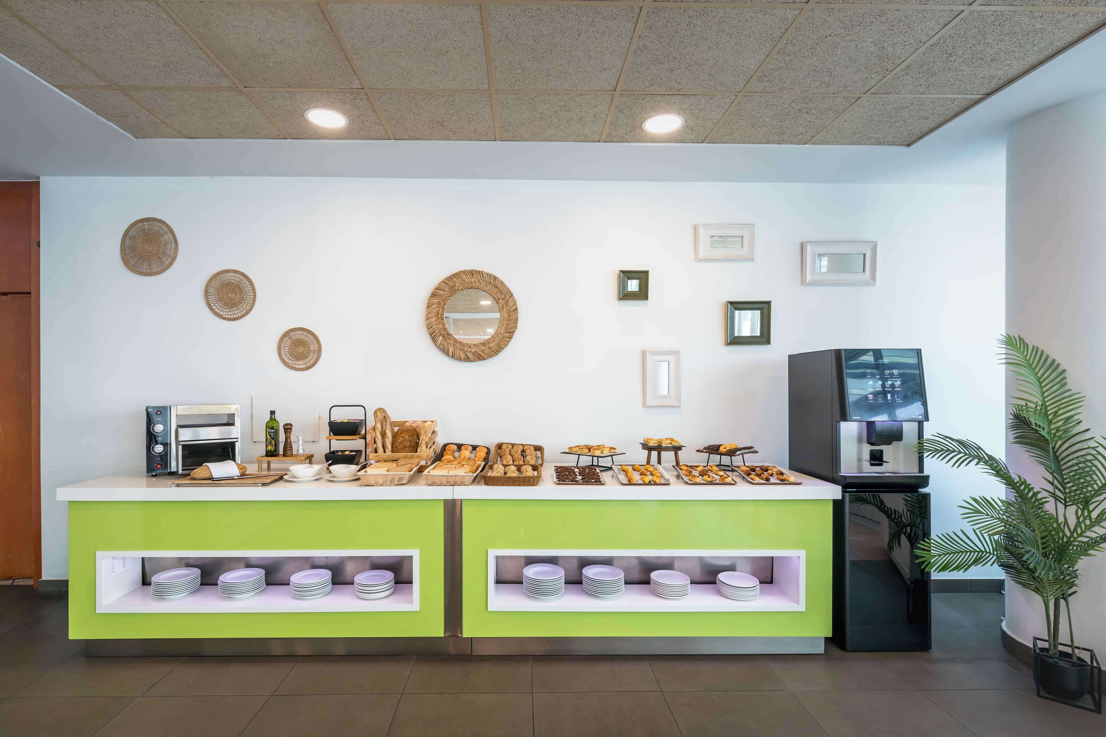 A buffet area with a variety of food items, a coffee machine, and a TV screen.