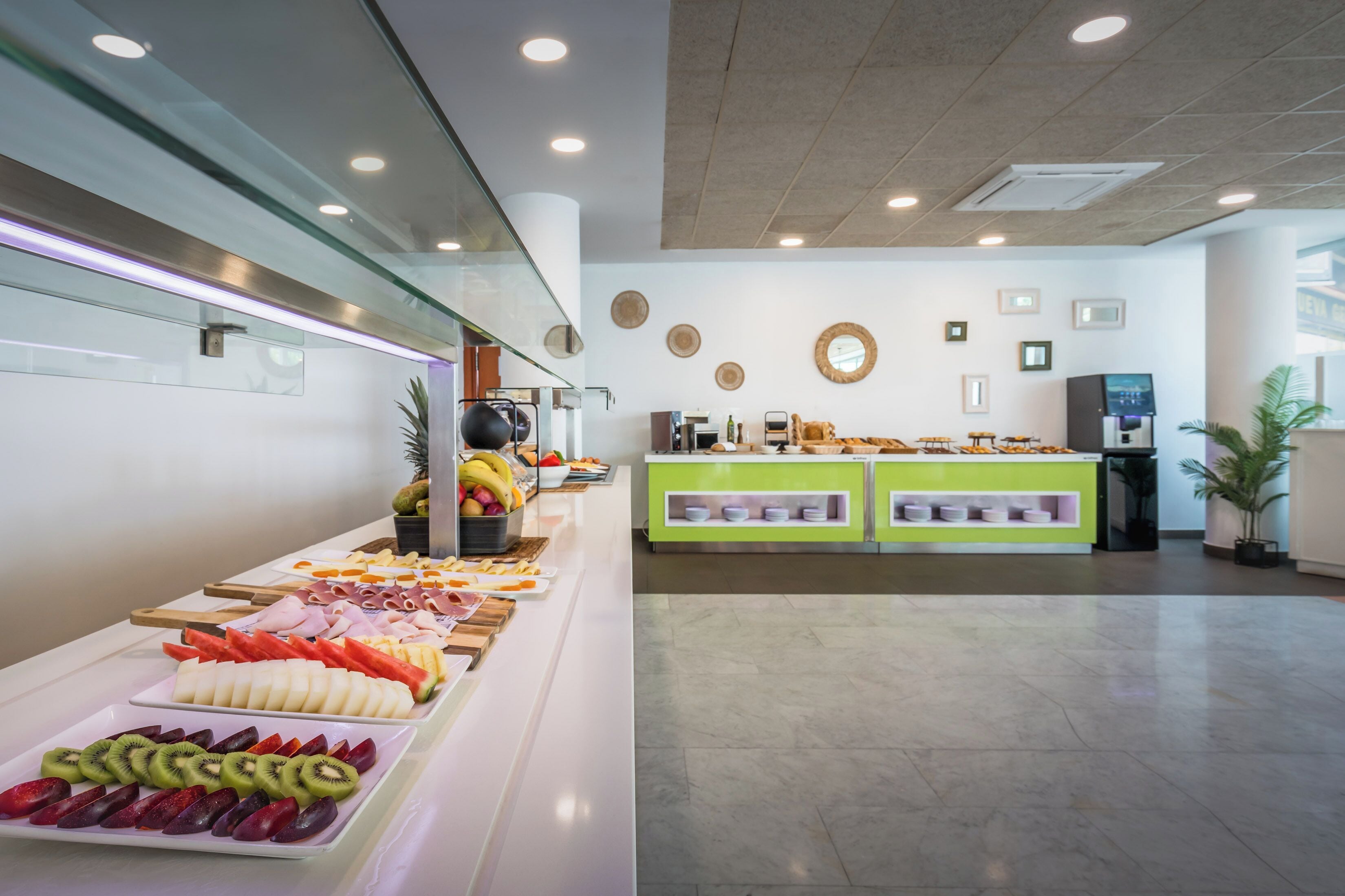 Zona de bufé con diversos alimentos y un mostrador verde.