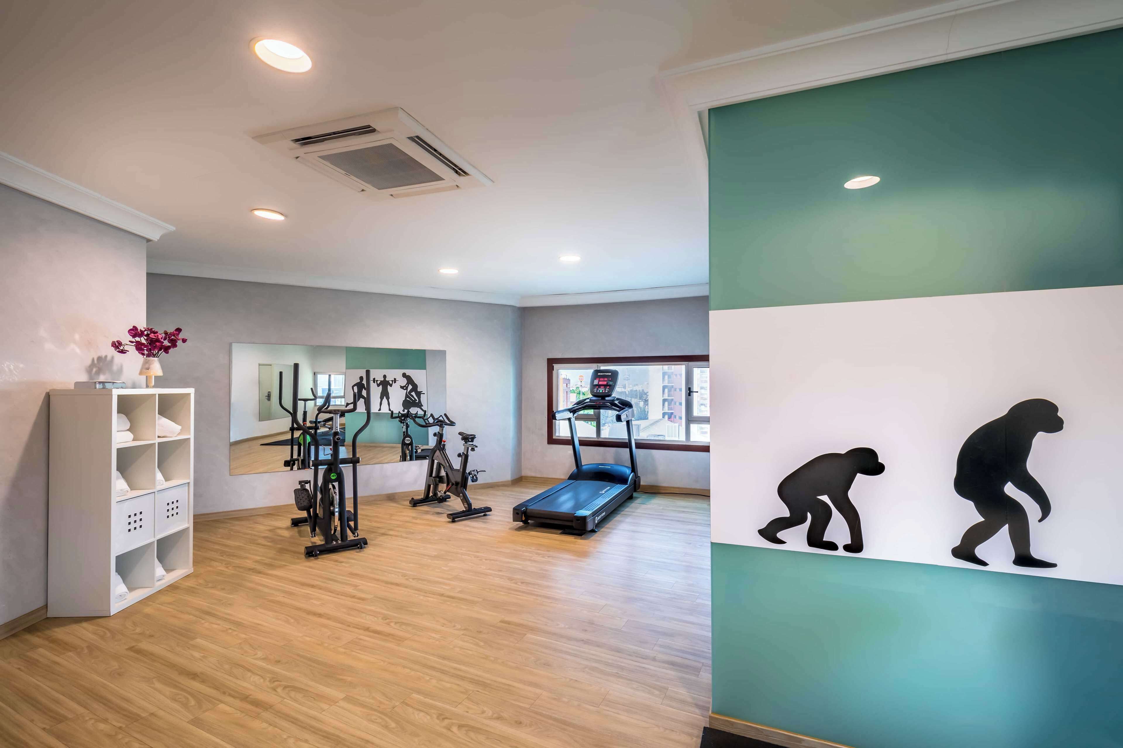 A gym with exercise equipment, a treadmill, and a mirror.