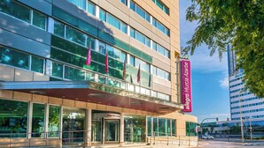 Un hôtel moderne doté d’une entrée imposante, de grandes fenêtres et offrant une vue dégagée sur le paysage urbain environnant.