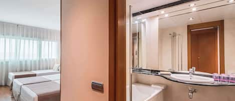 A hotel room with two beds, a large mirror, a sink, and a shower.