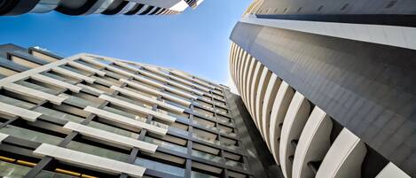 A modern high-rise building with a unique architectural design, featuring a series of balconies and a curved facade.