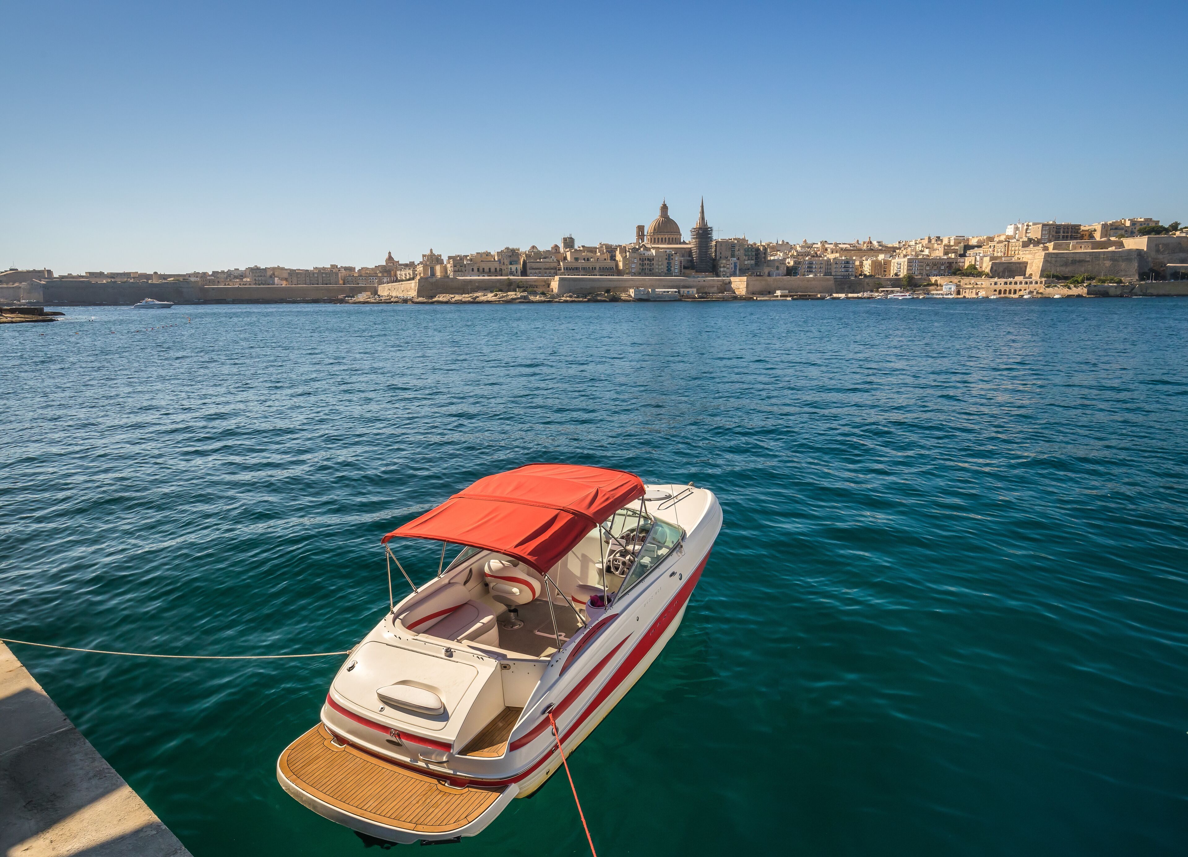 A boat docked near a waterfront with a cityscape in the background.