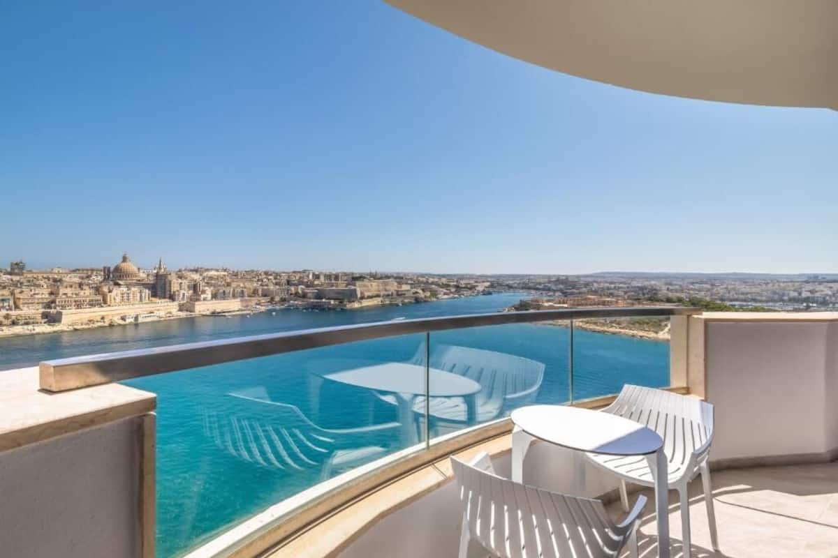 A balcony with a clear view of a cityscape and a body of water.