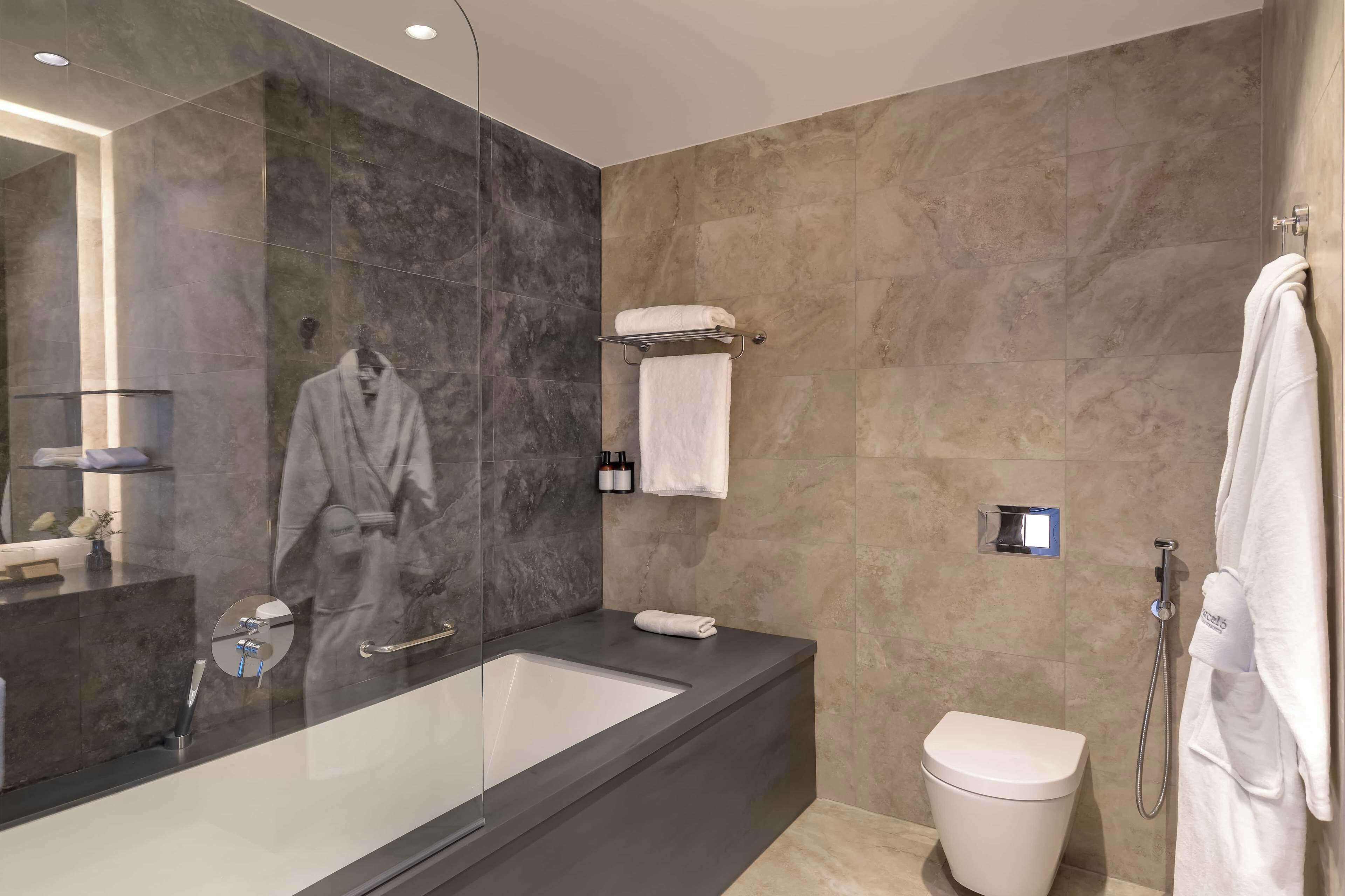A modern bathroom with a large bathtub, a toilet, and a glass-enclosed shower.