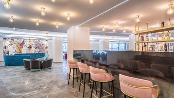 Eine moderne Bar mit hohen Hockstühlen, einer Sitzecke mit Sofas und einer Bar, die mit verschiedenen Flaschen bestückt ist.