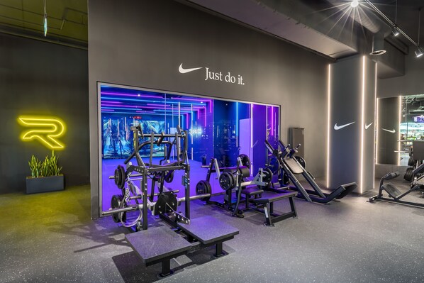 Un gimnasio moderno con diverso equipamiento de ejercicio, un letrero de neón y mensajes de motivación.