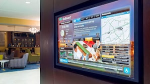 A digital display in a hotel lobby with a news ticker, a map, and various news categories. - Courtyard by Marriott Little Rock Downtown (Little Rock)