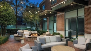 An outdoor patio area with wicker furniture, a round table, and a fire pit. - Courtyard by Marriott Little Rock Downtown (Little Rock)