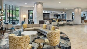 A spacious lobby with a curved sofa, patterned armchairs, and a round coffee table. - Courtyard by Marriott Little Rock Downtown (Little Rock)