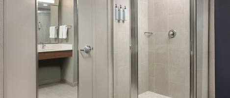 A modern bathroom with a glass-enclosed shower, a vanity with a mirror, and a toilet.