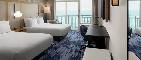 A hotel room with two beds, a desk, a chair, a TV, and a balcony with a view of the sea.