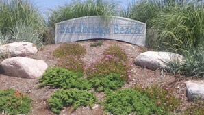 A sign for Sandbridge Beach with surrounding landscaping and rocks. - Fairfield Inn & Suites by Marriott Virginia Beach Oceanfront (Virginia Beach)