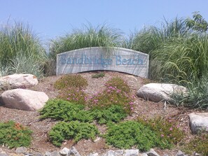 A sign for Sandbridge Beach with surrounding landscaping and rocks. - Fairfield Inn & Suites by Marriott Virginia Beach Oceanfront (Virginia Beach)