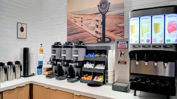 Una estación de café con varios dispensadores de café, un enfriador de agua y un dispensador de jugo.