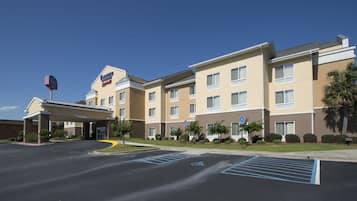 Un hotel de varios pisos con entrada cubierta, estacionamiento y plazas de aparcamiento reservadas para discapacitados.