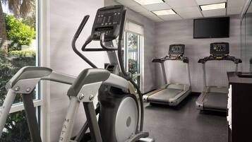 Un gimnasio con cintas de correr, elíptica y bicicleta estática.