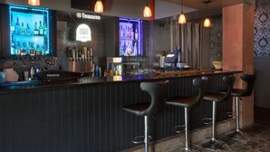 A bar area with a Hennessy cooler, multiple liquor bottles, and bar stools. - Hilton Garden Inn Salt Lake City/Layton (Layton)