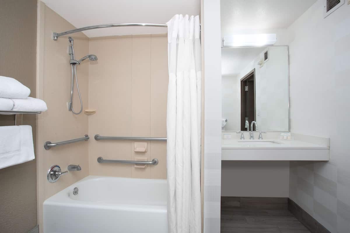A modern bathroom with a bathtub, shower, and vanity with a mirror.