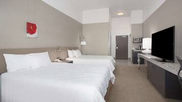 A hotel room with two beds, a TV, a desk, and a microwave.