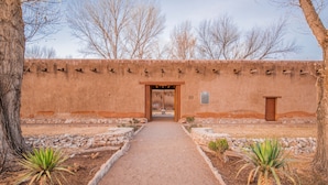 A pathway leading to a building with a rustic exterior, a wooden door, and a stone wall.