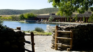 A stone pathway leading to a pool area with lounge chairs and a building in the background.