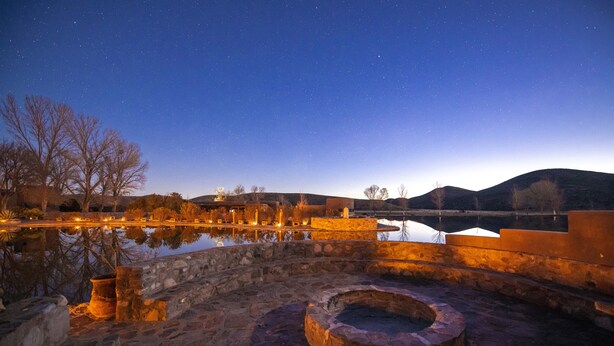 A stone courtyard with a reflective pool, stone walls, and a circular stone feature.