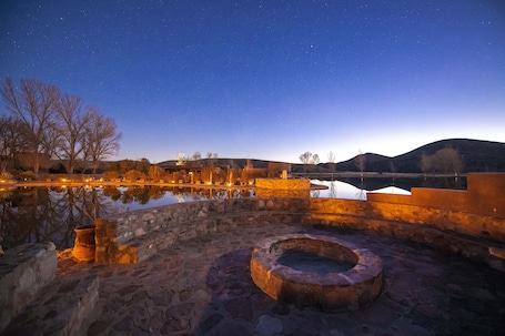 A stone courtyard with a reflective pool, stone walls, and a circular stone feature.