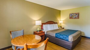 Une chambre d’hôtel avec un lit en bois, une table ronde, deux chaises, une table de chevet et une carte géographique accrochée au mur.
