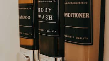 Tres botellas de gel de baño, champú y acondicionador colgadas en una pared.