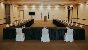Une salle de conférence avec une longue table, des chaises et un pupitre.