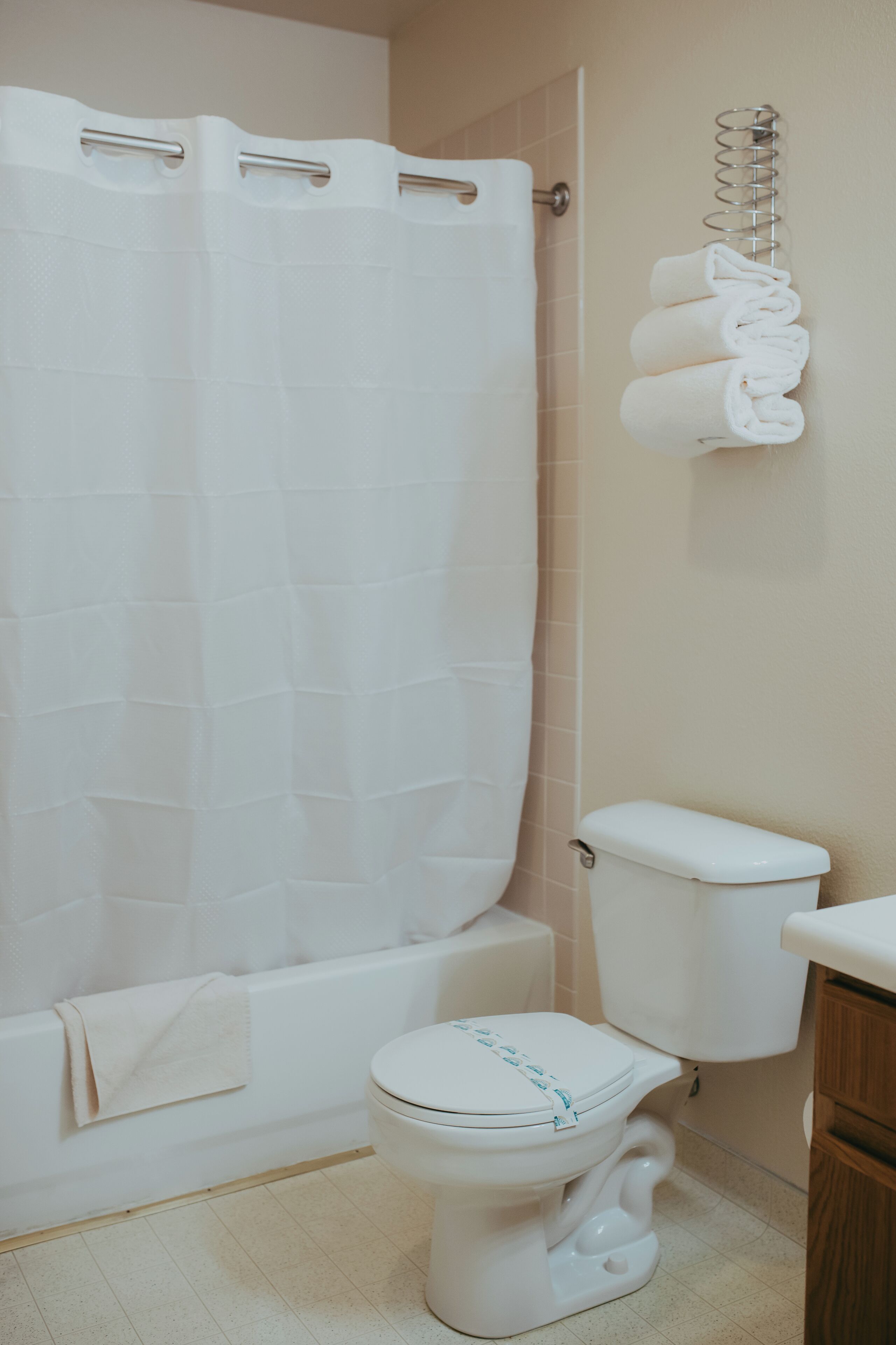 A bathroom with a white bathtub, toilet, and a towel rack with folded towels.