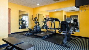Un gimnasio con equipo de ejercicio, un espejo grande y una televisión.