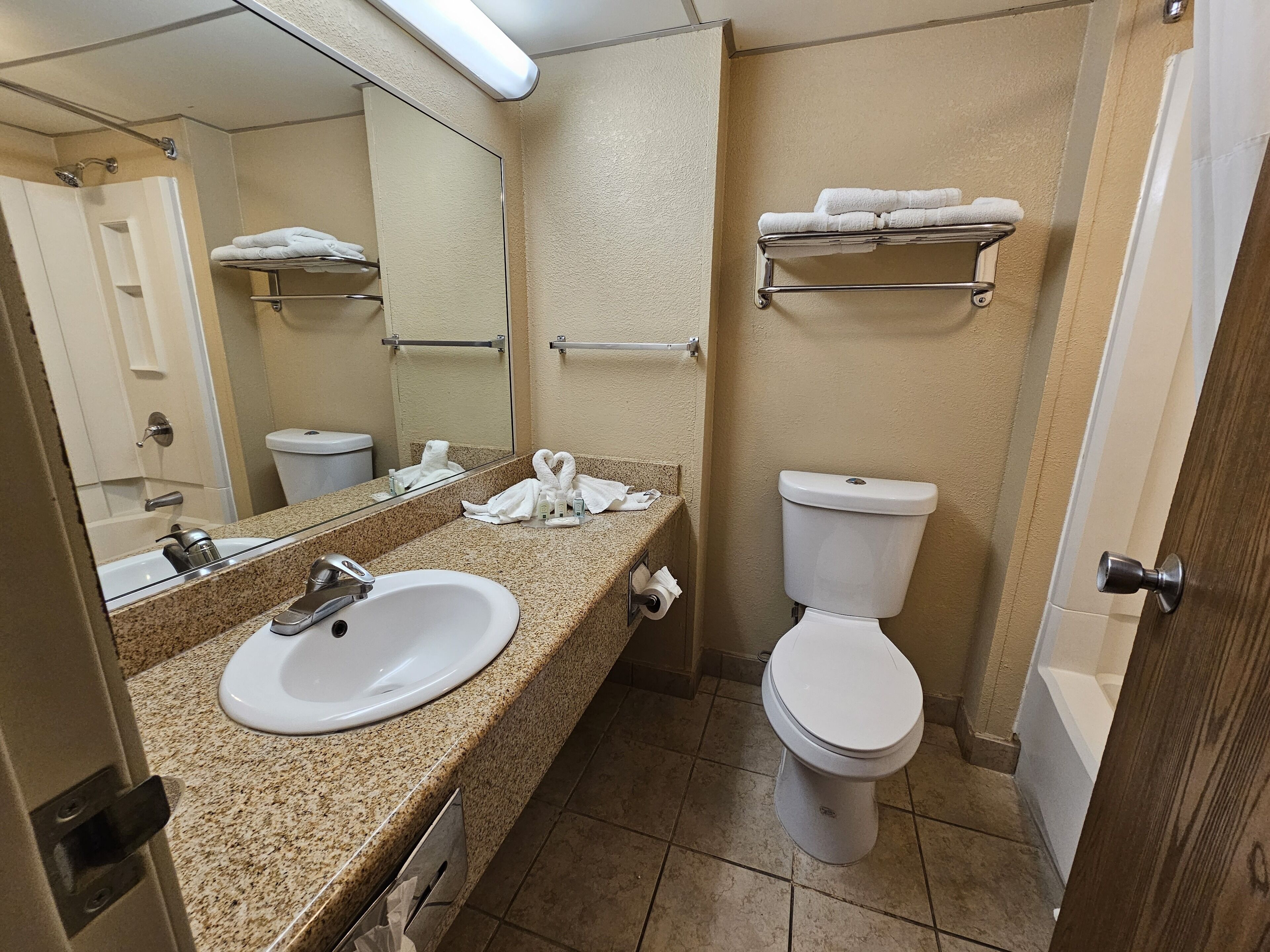 A bathroom with a sink, mirror, toilet, and towel rack.