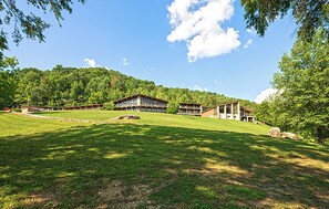 A large, modern building with multiple levels and a flat roof, surrounded by lush green grass and trees. - Buckhorn Lake State Resort Park (Buckhorn)