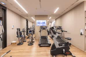Une salle de sport équipée de tapis de course, d’appareils elliptiques et de vélos d’appartement.