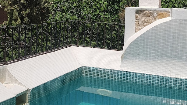 Una piscina con vistas a un puente de piedra histórico y edificios al fondo.